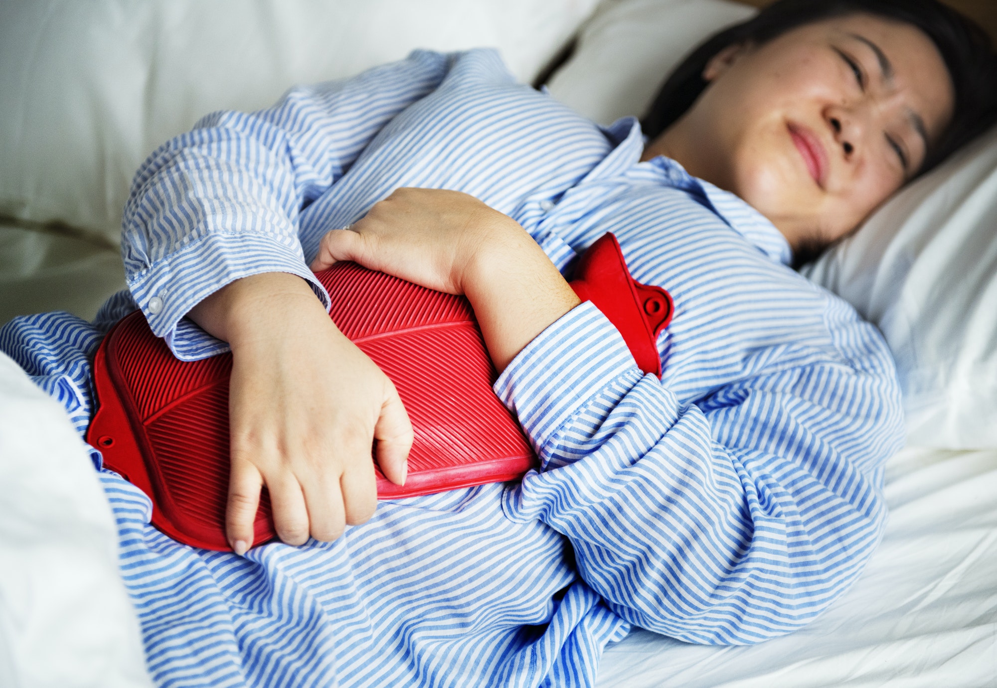 A woman in pain holding a hot water bottle
