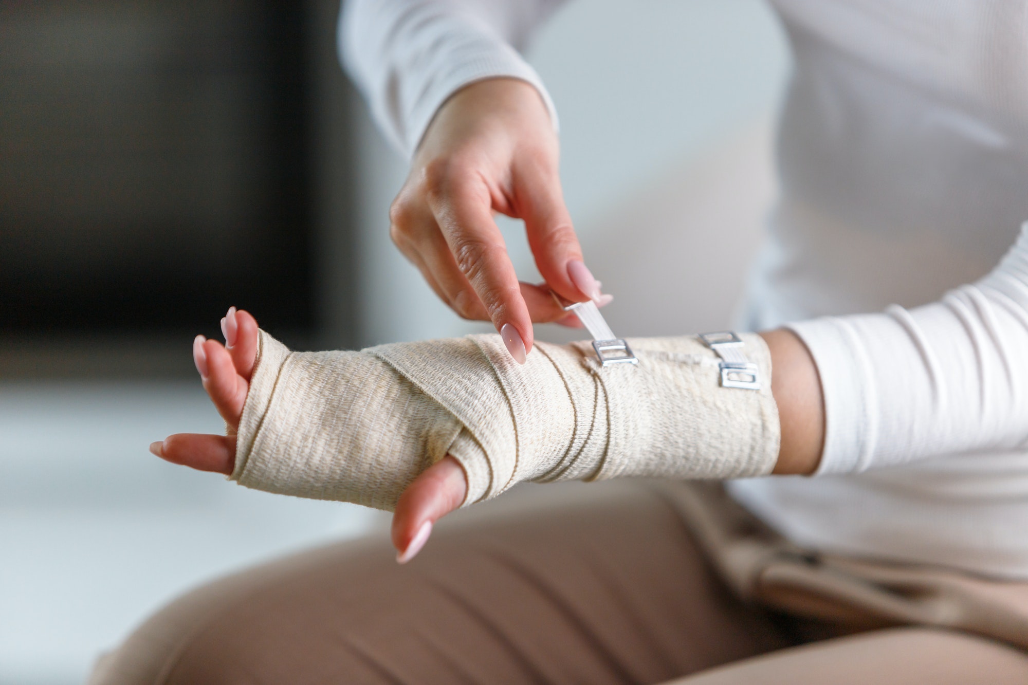 woman wrapping her painful wrist with elastic orthopedic bandage